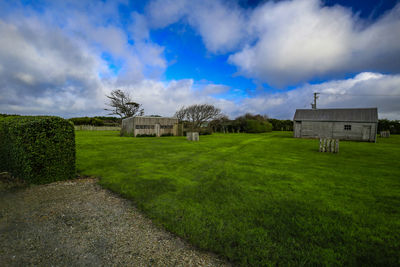 Built structure on grassy field by houses against sky