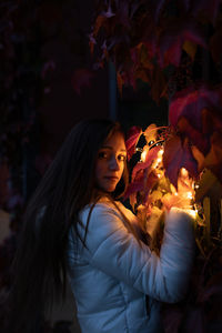 Portrait of young woman holding illuminated string light