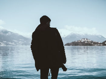 Rear view of man looking at sea against sky