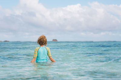 Rear view of woman standing in sea against sky