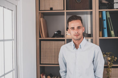 Portrait of young man standing against wall