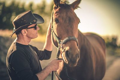 Side view of man holding horse leash 