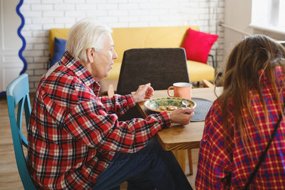 Rear view of woman using digital tablet while standing at home