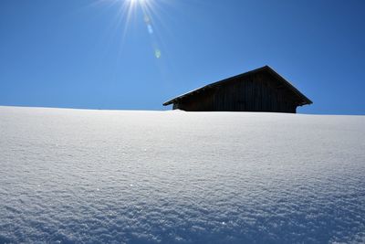 Built structure on snow covered landscape against blue sky