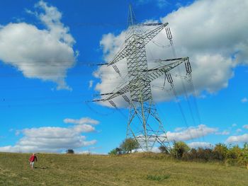 Low angle view of electricity pylon on field against sky