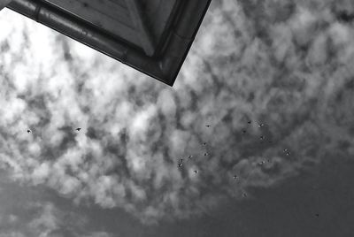 Low angle view of airplane flying against cloudy sky