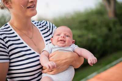 Close-up of mother carrying baby outdoors