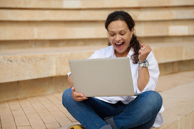 Young woman using laptop while sitting on steps