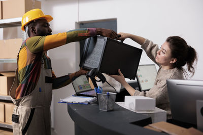 Side view of woman using laptop while standing in office