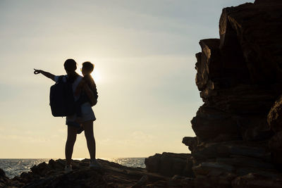 People standing on rock by sea against sky