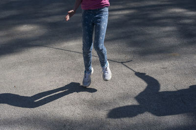 Low section of girl jumping on road