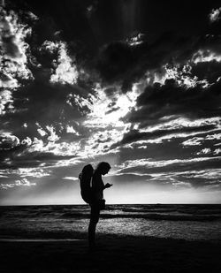 Silhouette man standing on beach against sky