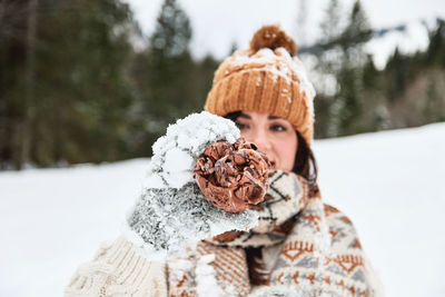 Winter portrait of a young woman. winter clothes, snow. holding chocolate snowball.