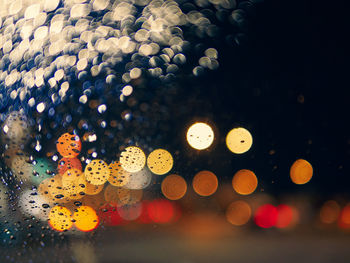 Defocused image of illuminated lights on wet glass