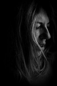 Close-up of woman with eyes closed against black background