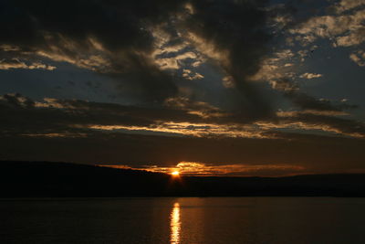 Scenic view of sea against dramatic sky during sunset