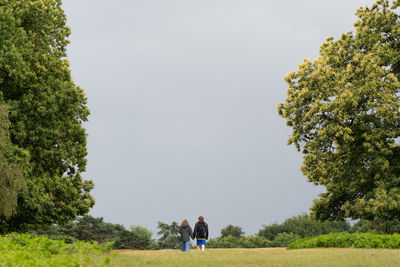 Rear view of people on field against sky