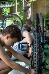 Boys repairing bicycle in yard