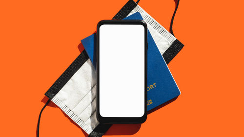 Close-up of smart phone against orange background