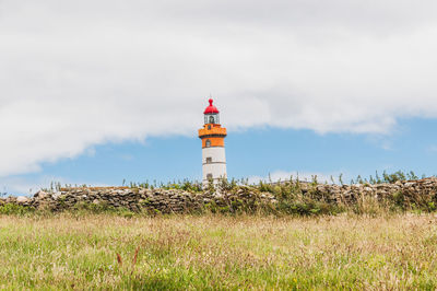 Lighthouse on field against sky