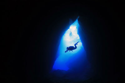 Low angle view of silhouette man swimming in sea