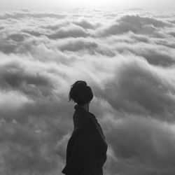 Side view of woman standing against cloudy sky