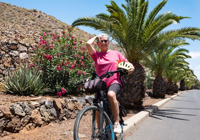 Smiling senior woman with bicycle on road