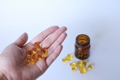 Close-up of hand holding bottle against white background