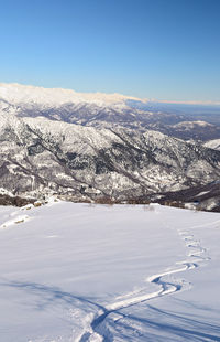 Aerial view of snow covered landscape against blue sky