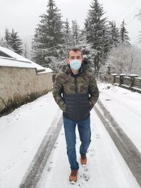 Full length portrait of man standing on snow covered field