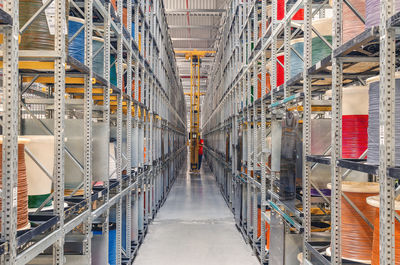 Interior of modern storage warehouse with coils of colored cable on metal shelves. forklift lift 