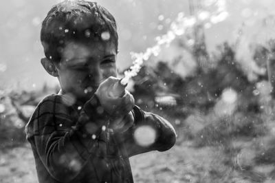 Little boy is playing water with hose outside