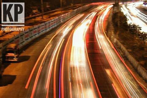 ILLUMINATED LIGHT TRAILS ON HIGHWAY AT NIGHT