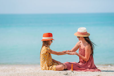 Woman wearing hat on beach against sky