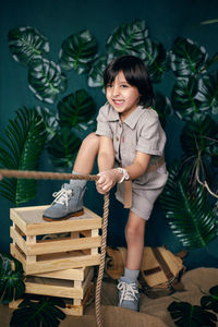 Boy child traveler in linen clothes pull a rope stands in the studio