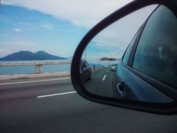 Reflection of clouds on side-view mirror of car