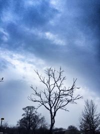 Low angle view of bare tree against cloudy sky