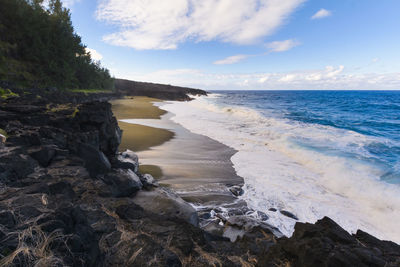 Wild beach with volcanic rocks at reunion island with a blue sky