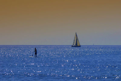 Silhouette of man paddleborading on sea during sunset