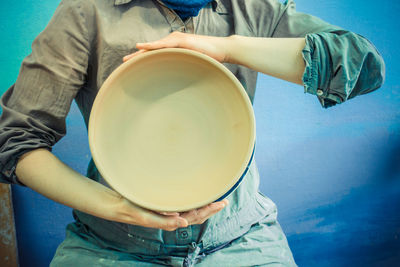 Master potter holds round clay plate in his hands.potter's body. sculptor sculpts pots  