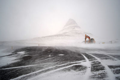 Person riding horse on snow covered mountain against sky