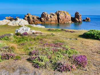 Scenic view of rocks by sea against sky