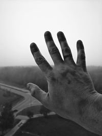 Close-up of hand against sky