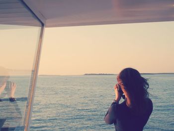 Young woman on beach against sky during sunset