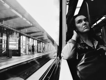 Thoughtful woman looking through window while traveling in train