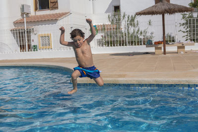 Excited child leaps into the swimming pool, enjoying summer.