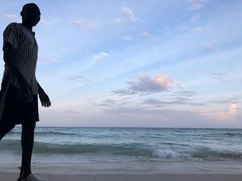 Man standing at beach against sky