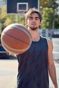 Portrait of young man showing basketball