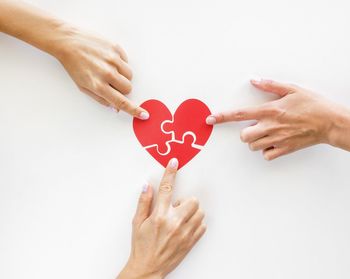 Midsection of woman holding heart shape over white background
