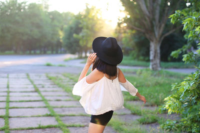 Woman wearing hat standing against plants